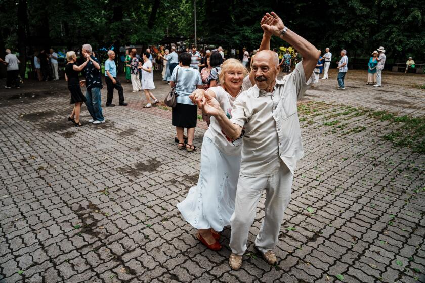 KYIV, UKRAINE -- JUNE 24, 2023: Larysa Zeltinya, left and Arkadii, last name not given, dance as they join other elderly residents who come out every weekend to dance together during summertime at the Hydropark in Kyiv, Ukraine, Saturday, June 24, 2023. With the Ukraine war in its 17th month, ongoing stress is exhausting for everyone. In the capital, Kyiv, as elsewhere in the country, people find ways to cope. (MARCUS YAM / LOS ANGELES TIMES)