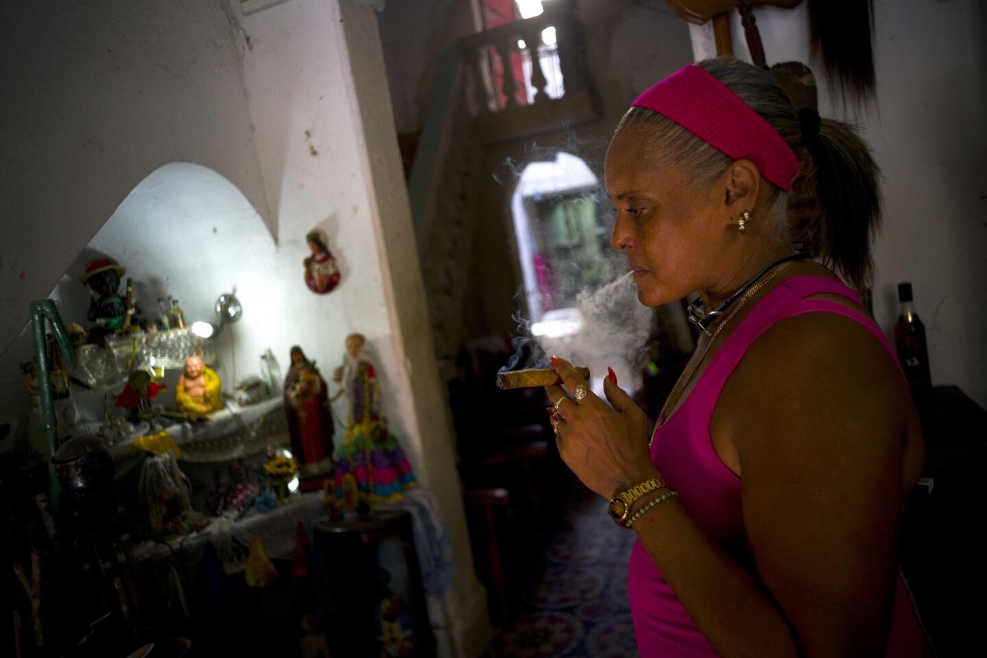Juliana Natividad Hernández enciende un cigarro frente a un altar en su tienda de objetos religiosos en La Habana, Cuba. Las tiendas especializadas en artículos religiosos, desde la santería hasta el catolicismo, abundan tras las reformas impulsadas por el gobierno.