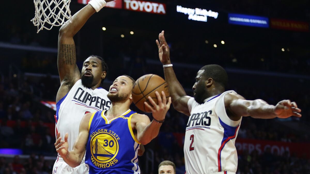 Warriors guard Steph Curry slips past Clippers defenders DeAndre Jordan, left, and Raymond Felton for a second-half basket while drawing a foul.