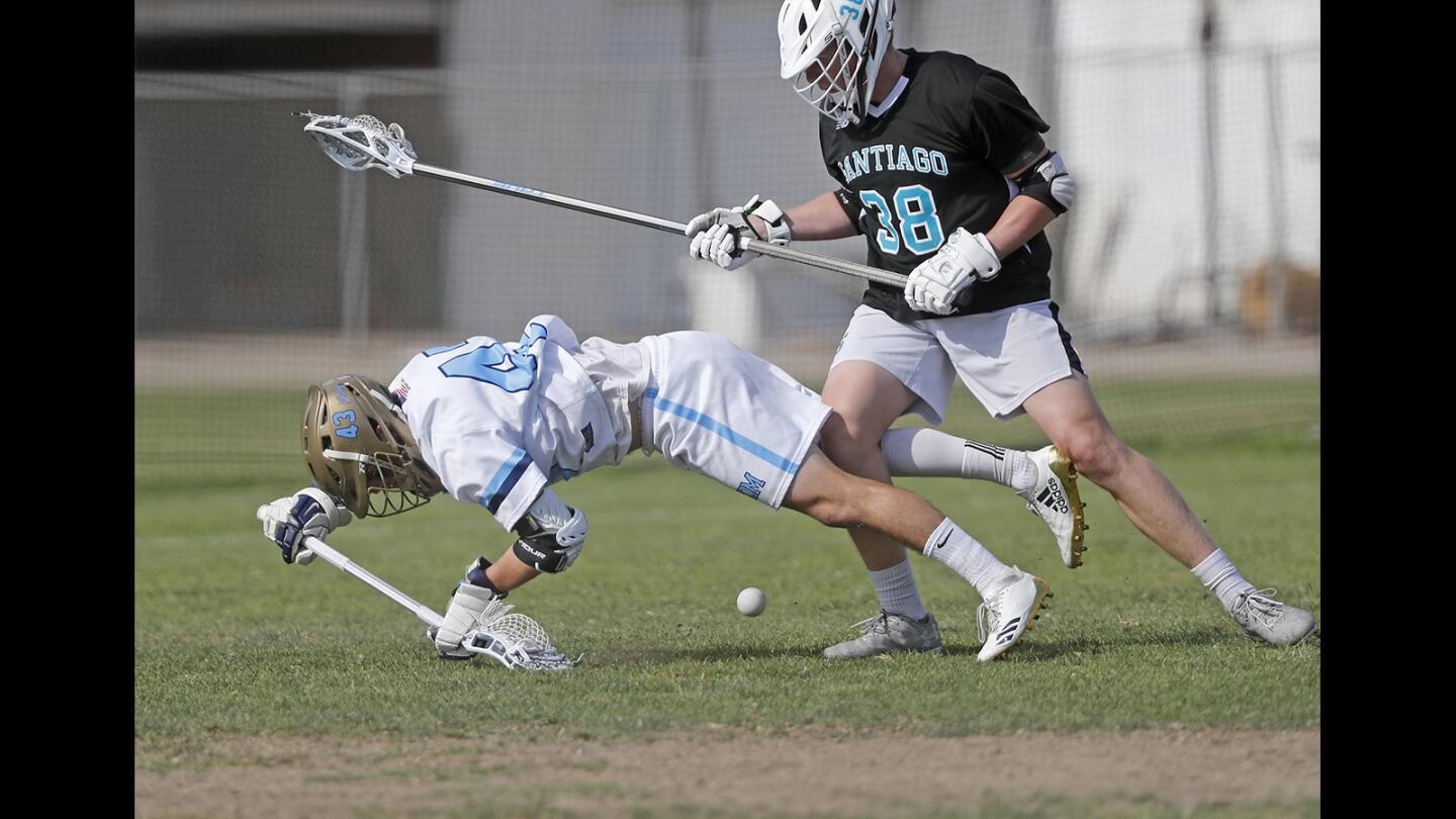 Corona del Mar High's Eric Fries, left, is checked by a Santiago defender during first half in the first round of the U.S. Lacrosse Southern Section South Division playoffs in Newport Beach on Tuesday, May 1.