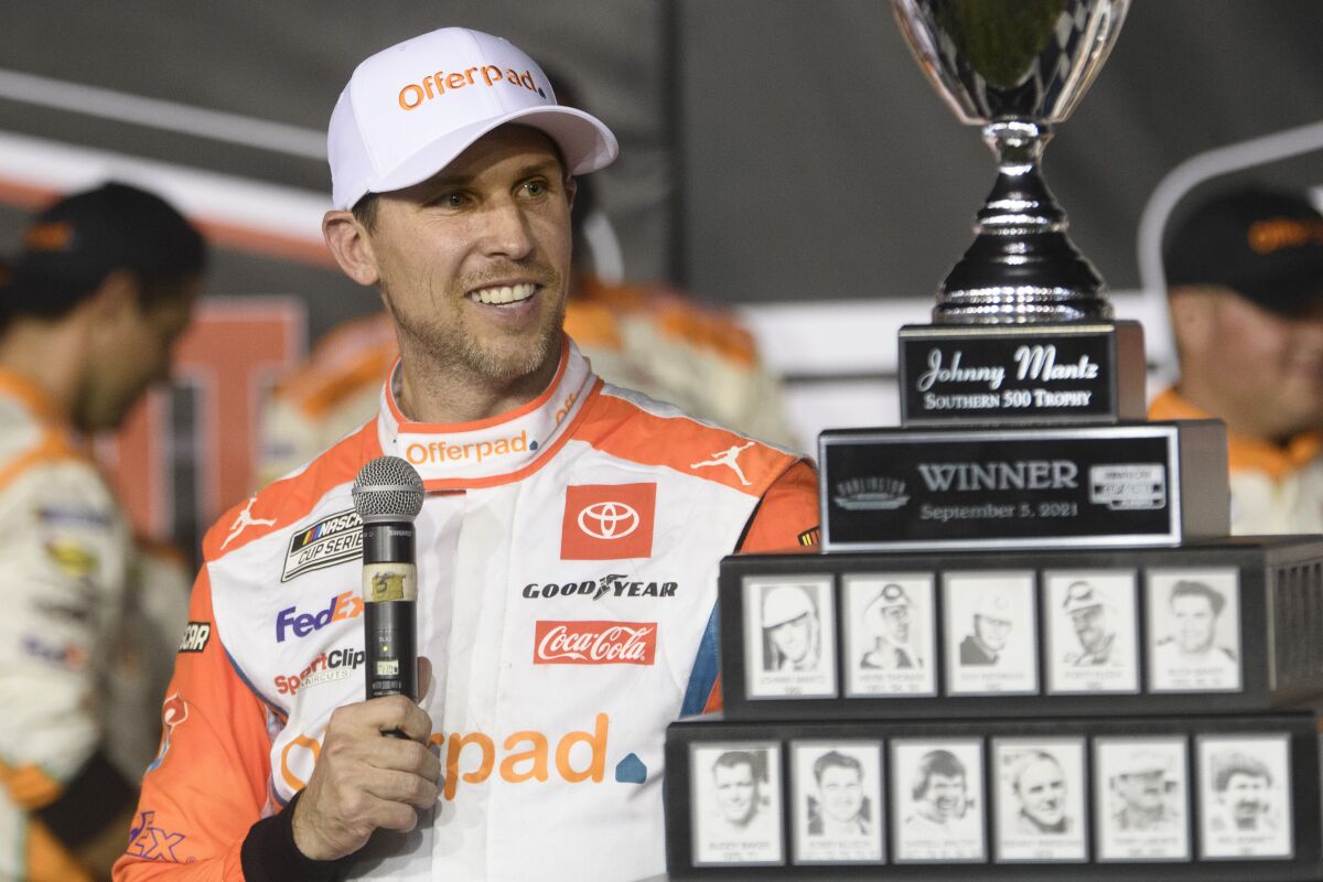 Denny Hamlin looks at the trophy after winning a NASCAR Cup Series auto race Sunday, Sept. 5, 2021, in Darlington, S.C. (AP Photo/John Amis)