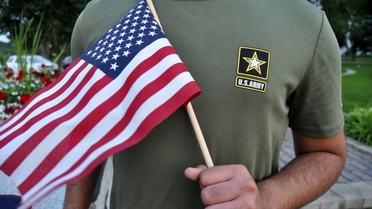 A Pakistani recruit, 22, who was recently discharged from the U.S. Army, holds an American flag. The Army has stopped discharging immigrant recruits who enlisted seeking a path to citizenship - at least temporarily.