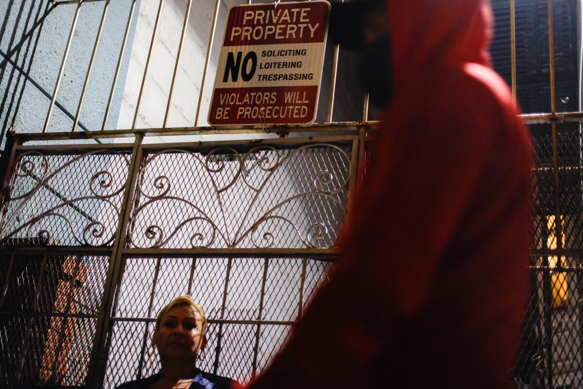 A sign on a wire fence prohibits loitering, soliciting and trespassing