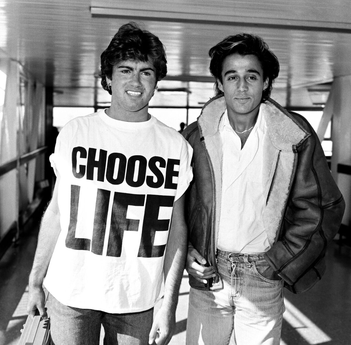 black and white photo of two men, the one on the left wearing a shirt saying "choose life"