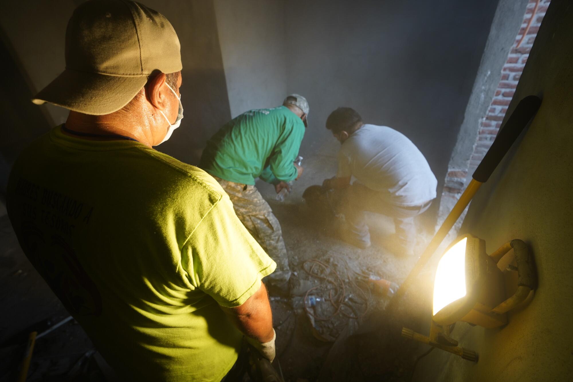 Jesus Varajas Chairez pours water as a volunteer cuts through a concrete floor with a saw.