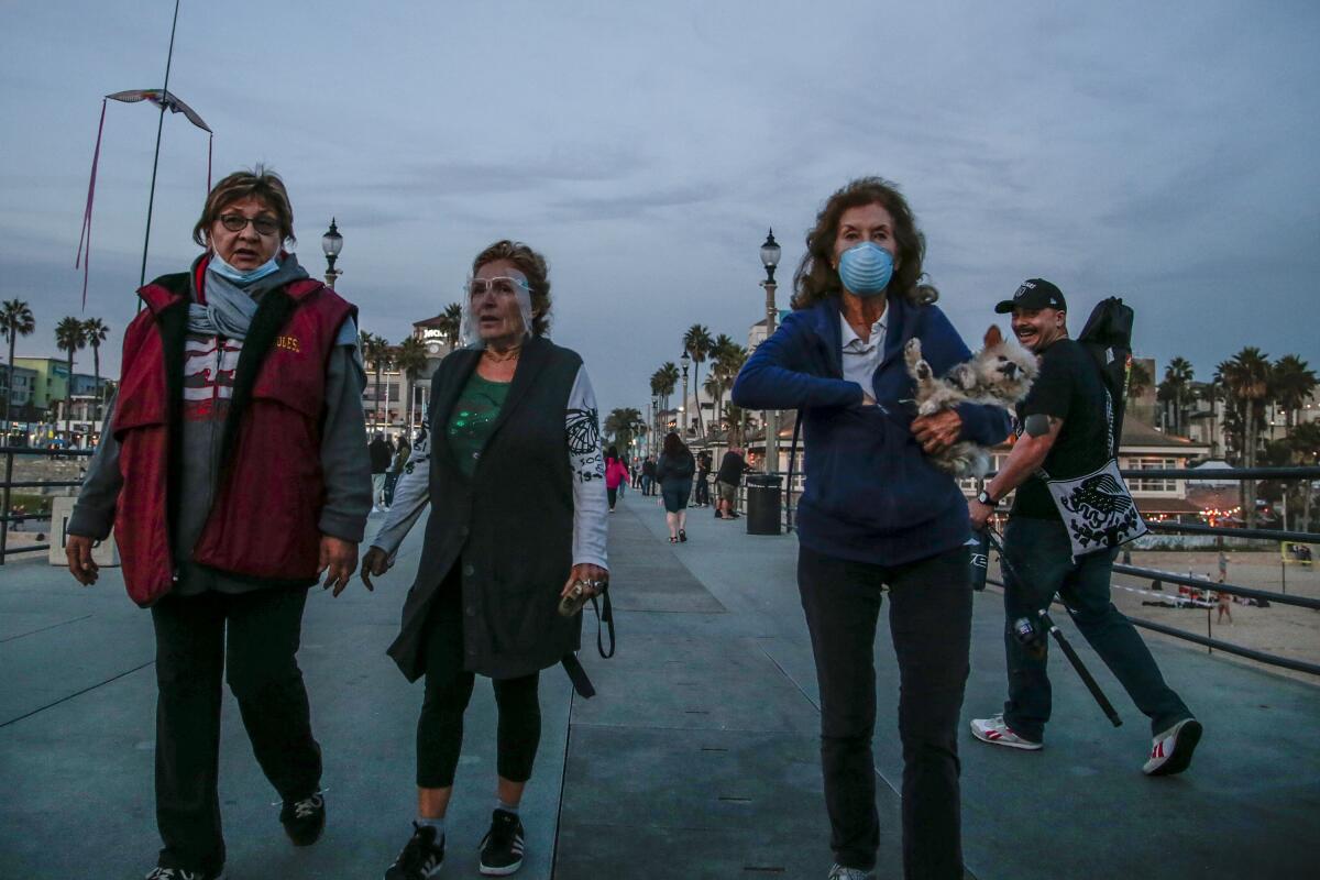 People walk on the Huntington Beach Pier on Saturday.