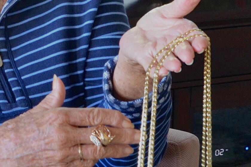 A victim of jewelry swap scam holds counterfeit necklaces and ring given to her by a thief.