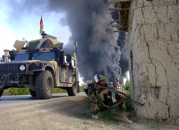 A member of the Afghan security forces keeps a look out as trucks carrying supplies to coalition forces burn after hundreds of people blocked a main road and set them on fire to protest what they said were civilian deaths in NATO operations in Logar province.