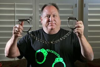 Mark Lyons of Encinitas holds a pair of Civil War-era handcuffs made by the Providence Tool Company. It's one of more than 1,000 pairs in his collection.
