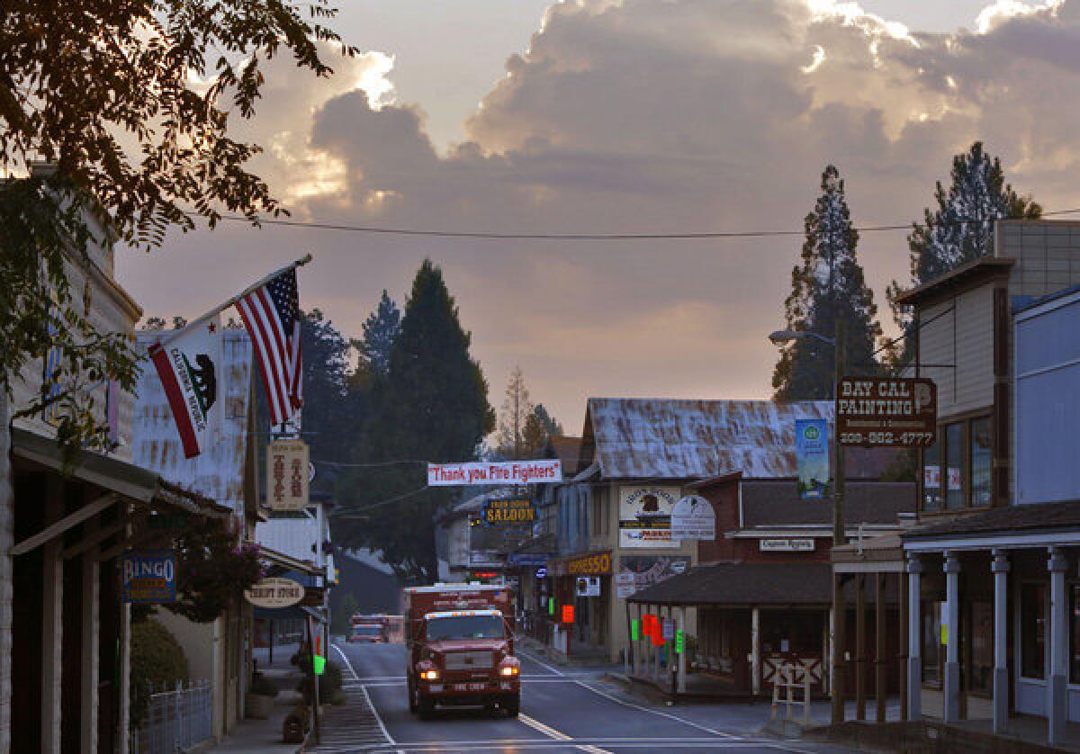 California Department of Forestry and Fire Protection trucks move through Groveland, Calif., under a banner that reads "Thank you Fire Fighters".