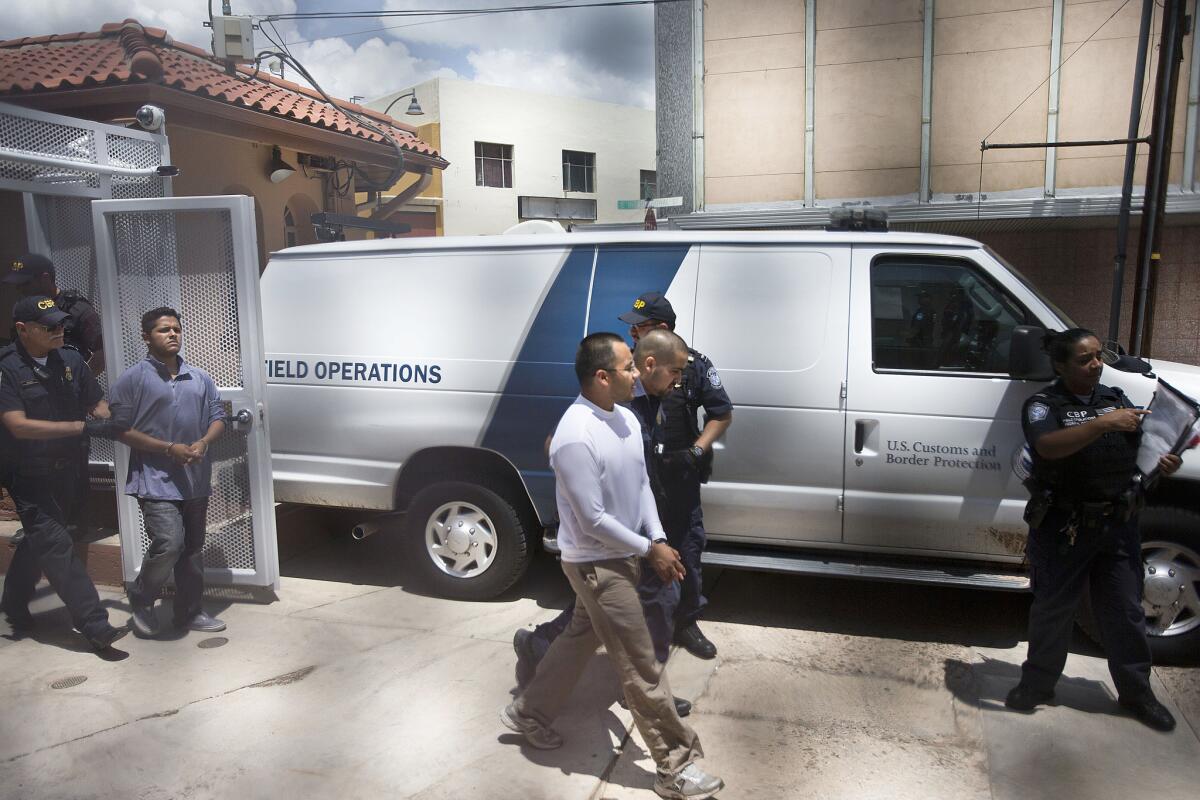 Immigration rights activists Marco Saavedra, 23, front, and Luis Leon, 20, in back, are led into a van by U.S. Customs and Border Protection agents in Nogales, Ariz. They were among nine activists who asked to be allowed to reenter the United States from Mexico on humanitarian grounds in a protest against U.S. immigration policies.
