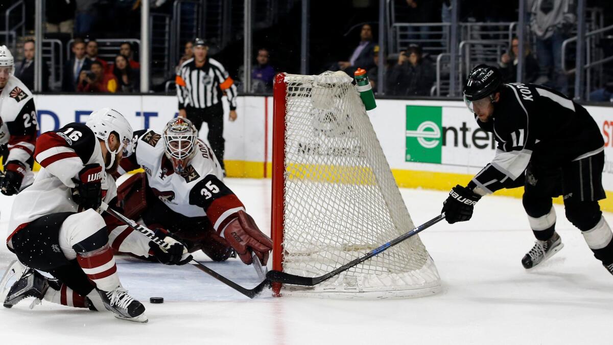 Kings center Anze Kopitar shoots from behind the net against Arizona left wing Max Domi and goalie Louis Domingue on March 14.