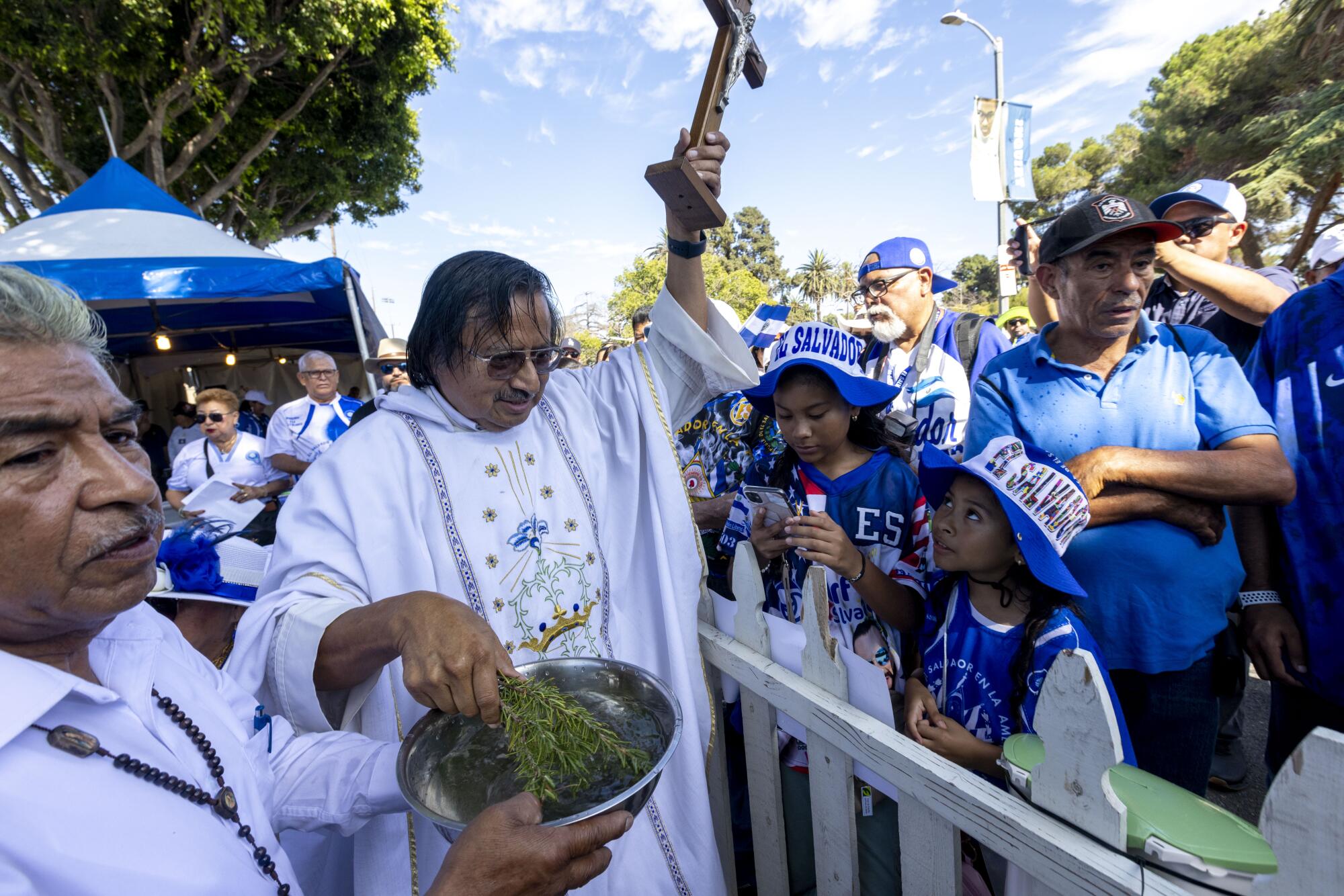El sacerdote Tomás López bendice a la multitud con agua bendita durante el servicio religi