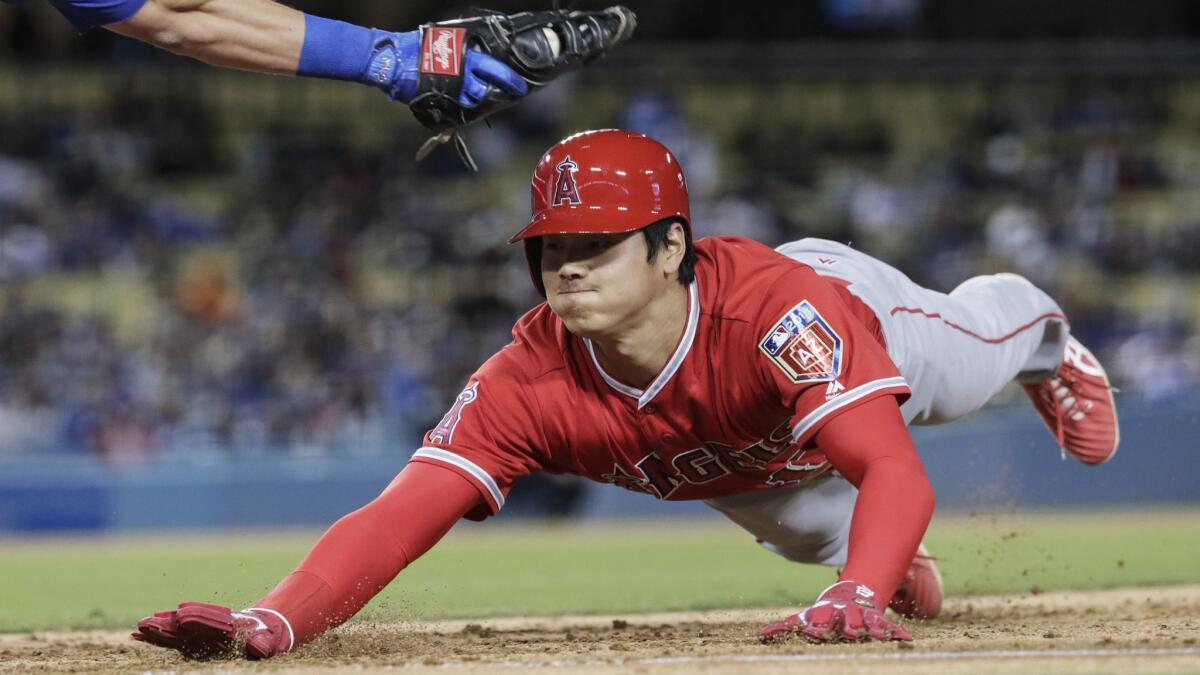 Angels designated hitter Shohei Ohtani dives under the tag of Dodgers first baseman Cody Bellinger on a fourth inning pickoff attempt by pitcher Rich Hill at Dodger Stadium.