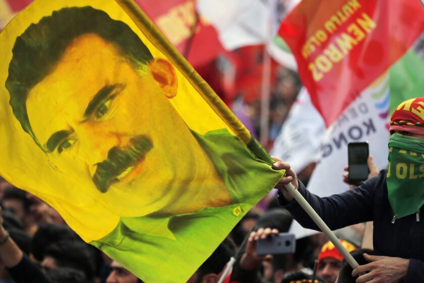 FILE - In this file photo dated Wednesday, March 21, 2018, a youth holds a flag with the image of Abdullah Ocalan, the jailed leader of the rebel Kurdistan Workers' Party, or PKK, in Istanbul, Turkey. It is announced Monday May 6, 2019, that imprisoned Kurdish rebel leader Abdullah Ocalan has called on hundreds of hunger-striking prisoners "not to endanger their lives." after a lawyer visited Ocalan on his prison island off Istanbul on May 2, the first time lawyers were able to see him since 2011. (AP Photo/Lefteris Pitarakis, FILE)