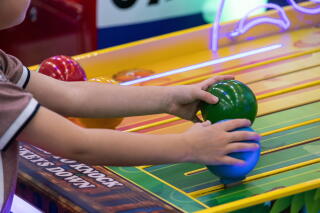 A child's hands holding green and blue balls on a game surface
