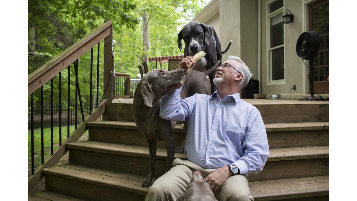 Brian Kursonis plays with his three dogs on his back porch at his home in Charlotte, NC. He says that being a caregiver for his dogs brings him lots of joy and prevents him from laying around all day.