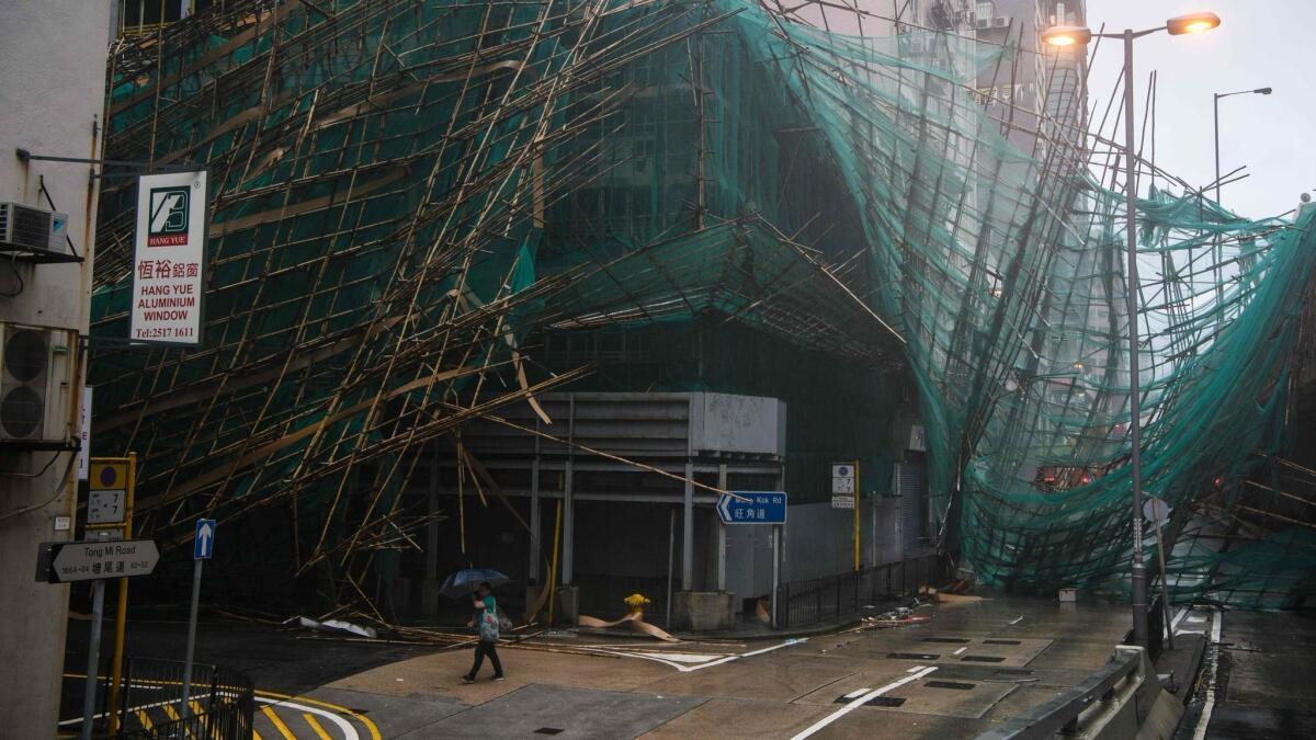 A woman uses her umbrella as she walks past collapsed bamboo scaffolding hanging from a building during Typhoon Mangkhut on Sunday in Hong Kong.