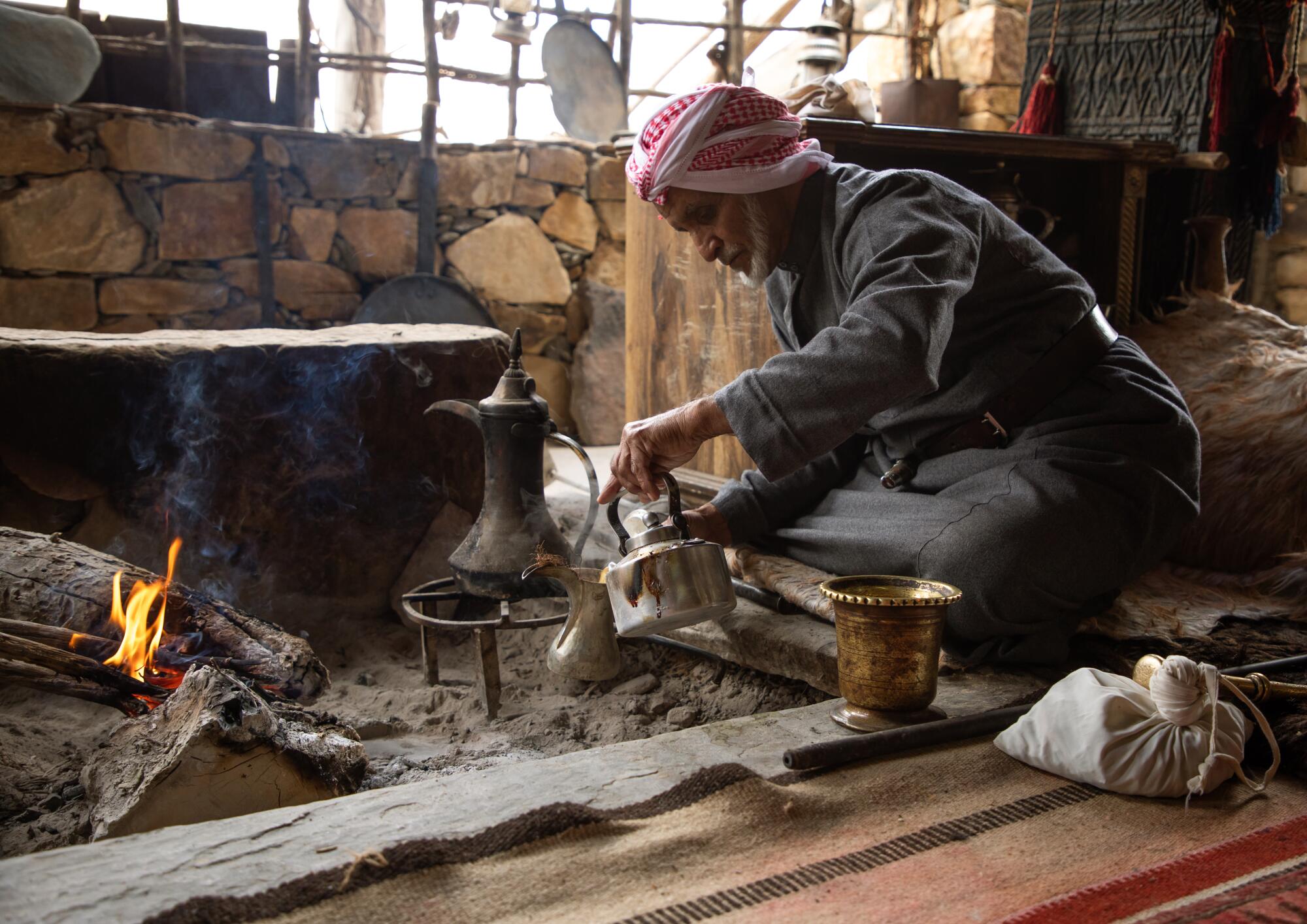  A Saudi man prepares coffee next to an open fire.