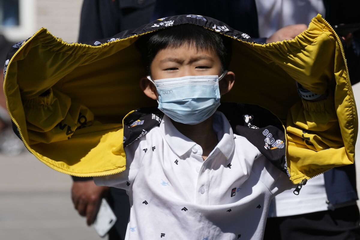 A child wearing a mask lines up for COVID test on Sunday, May 1, 2022, in Beijing. Many Chinese are marking a quiet May Day holiday this year as the government's zero-COVID approach restricts travel and enforces lockdowns in multiple cities. (AP Photo/Ng Han Guan)