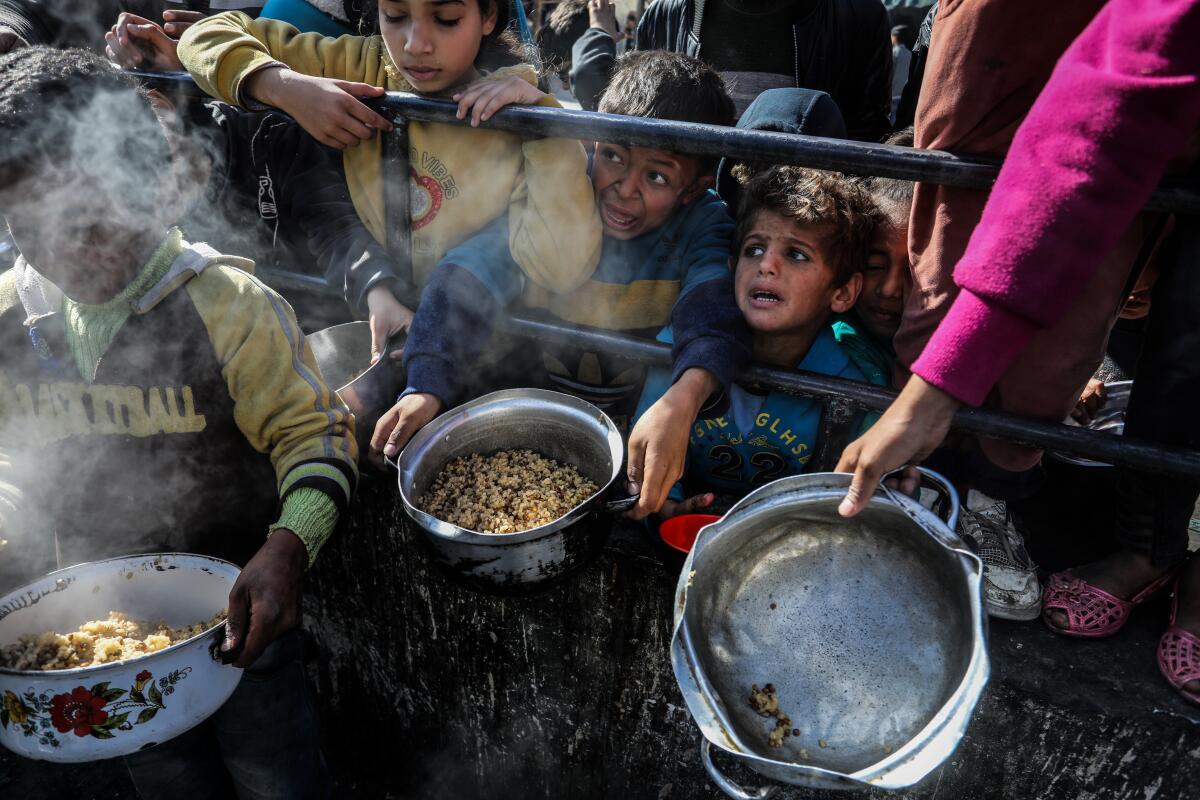 Displaced Palestinian children wait to receive food in Rafah, Gaza.