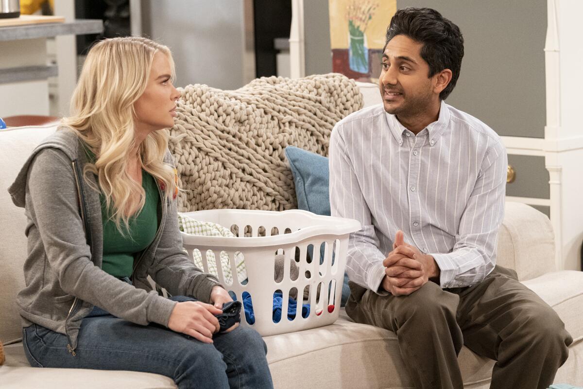 Kelli Goss and Adhir Kalyan sit on a couch in "United States of Al" on CBS.