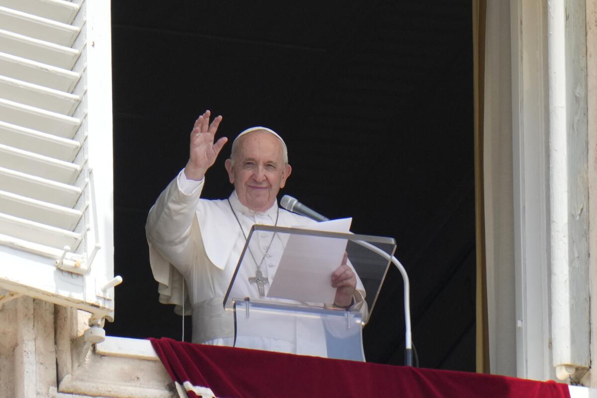 The pope waves from an open window.