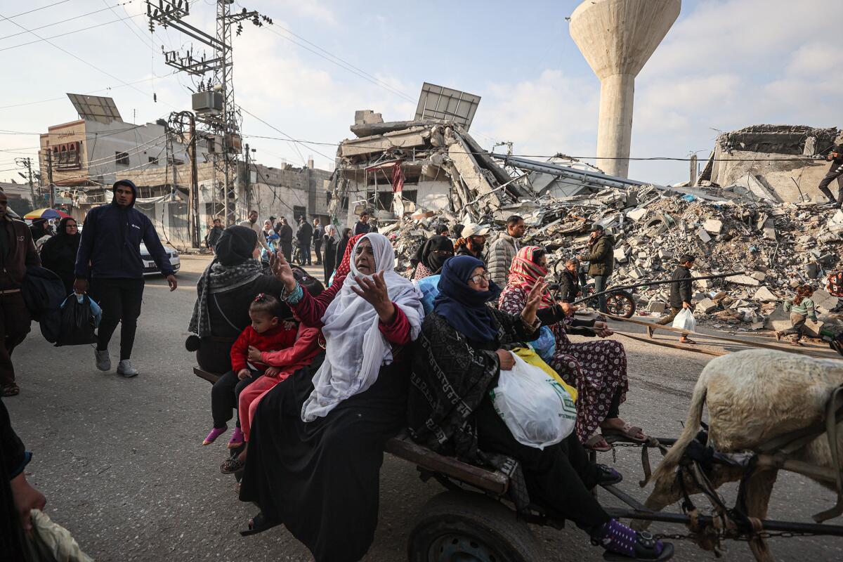 Palestinians ride with their belongings on a donkey cart amid the rubble of destroyed buildings in the Gaza Strip. 