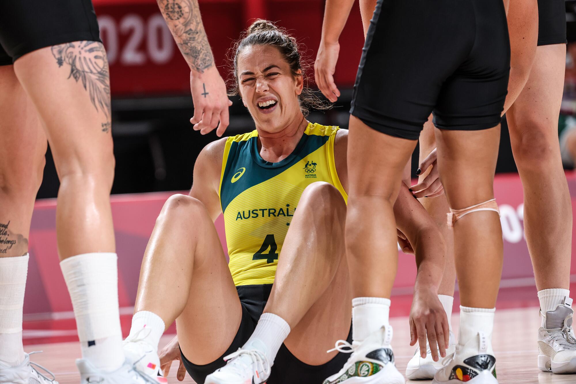 Australia guard Jenna O'Hea sits on the basketball court grimacing at the Tokyo Olympics.