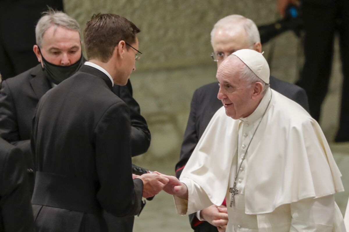 Pope Francis, right, greets a priest at the end of his weekly general audience in the Pope Paul VI hall at the Vatican, Wednesday, Oct. 14, 2020. (AP Photo/Andrew Medichini)