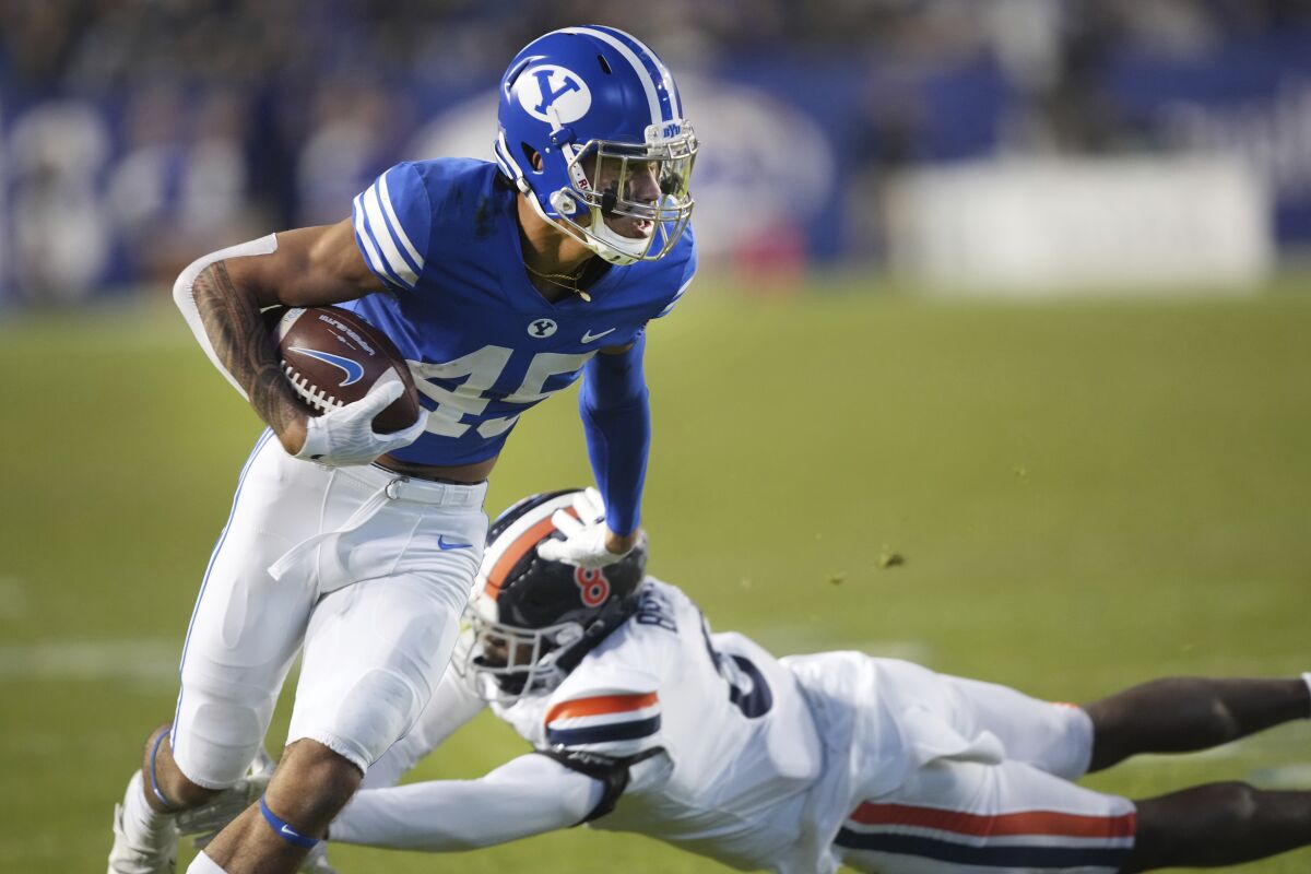 BYU wide receiver Samson Nacua (45) slips out of the attempted tackle of Virginia cornerback Darrius Bratton (8) during the first half of an NCAA college football game Saturday, Oct. 30, 2021, in Provo, Utah. (AP Photo/George Frey)