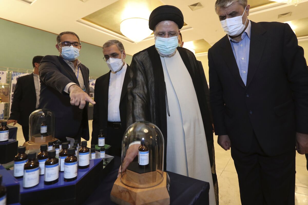 In this photo released by the official website of the office of the Iranian Presidency, President Ebrahim Raisi, second right, receives an explanation while visiting an exhibition of Iran's nuclear achievements in Tehran, Iran, Saturday, April 9, 2022. President Raisi said Saturday that Iran will continue nuclear activities as talks to revive Tehran's nuclear deal with world powers remain stalled. Head of the Atomic Energy Organization of Iran Mohammad Eslami, right, accompanies President Raisi. (Iranian Presidency Office via AP)