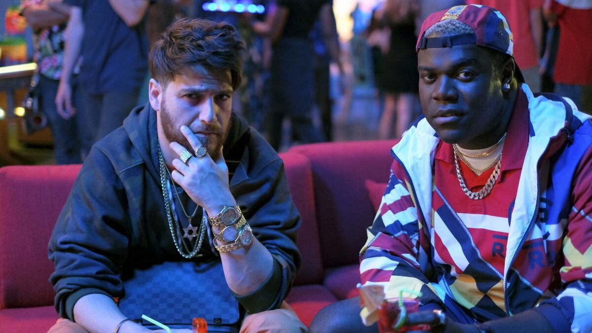 Adam Pally as Ronnie and Sam Richardson as Alf in the YouTube Premium comedy "Champaign ILL," about a pair of friends knocked back from the hip-hop high life to the normalcy of their hometown.