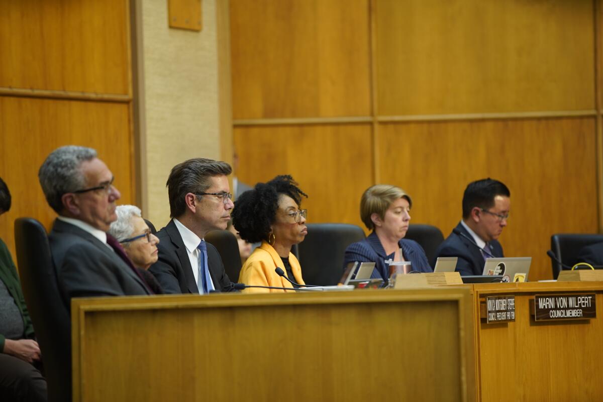 Six members of the San Diego City Council sit in chambers listening to people speak.