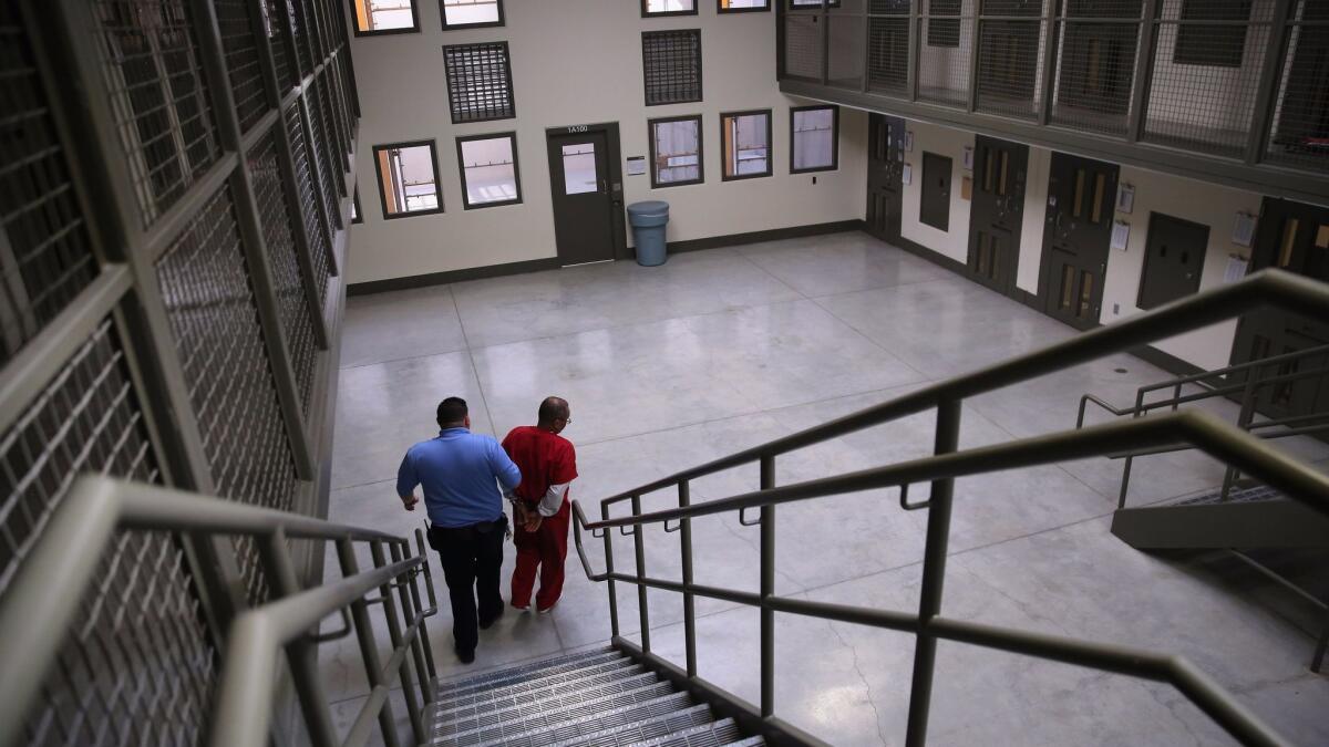 Un guardia acompaña a un inmigrante detenido desde una unidad de vivienda segregada a la población general, en el Centro de Detención de Adelanto, en 2013 (John Moore / Getty Images).