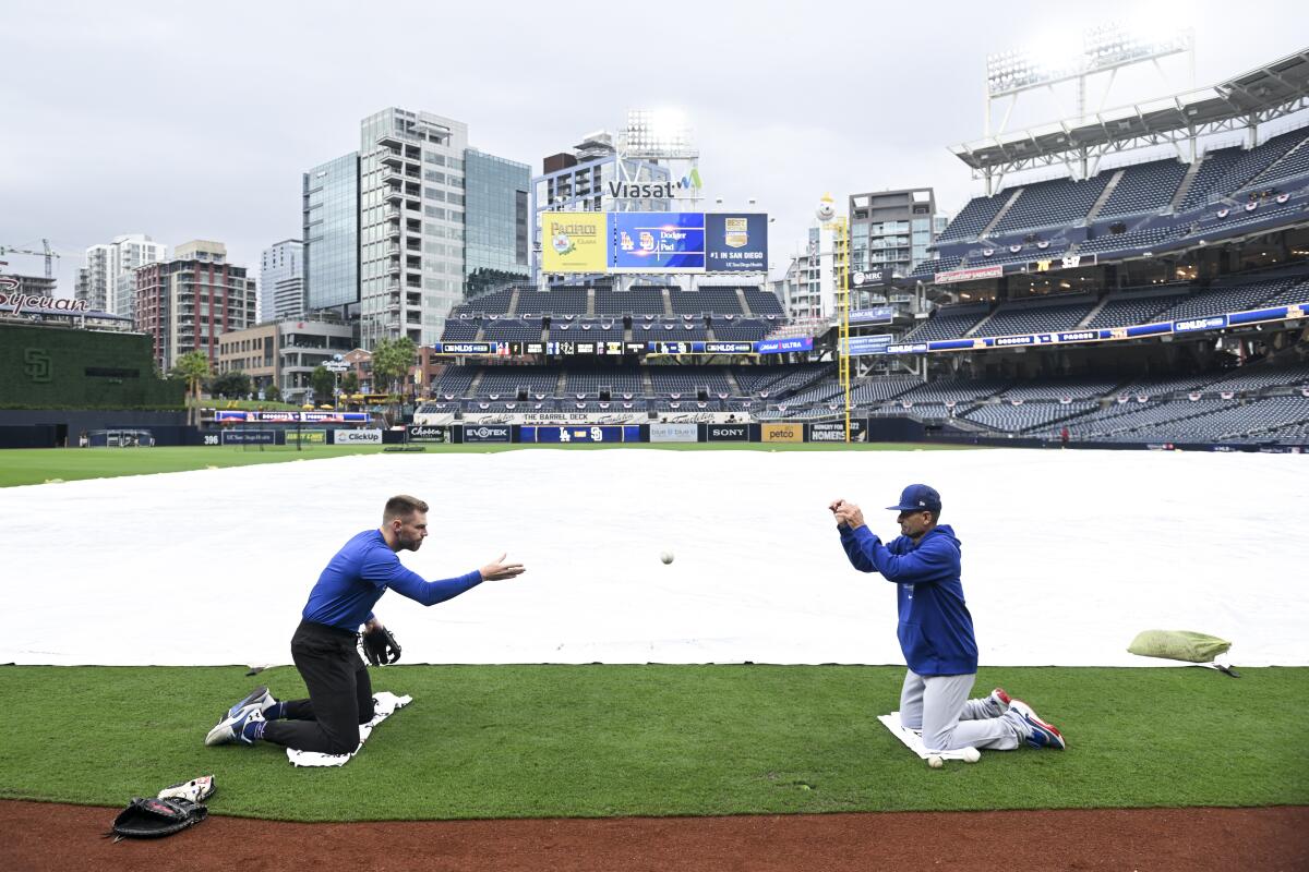 Dodgers first baseman Freddie Freeman goes through drills with third base coach Dino Ebel in front of a tarped infield.