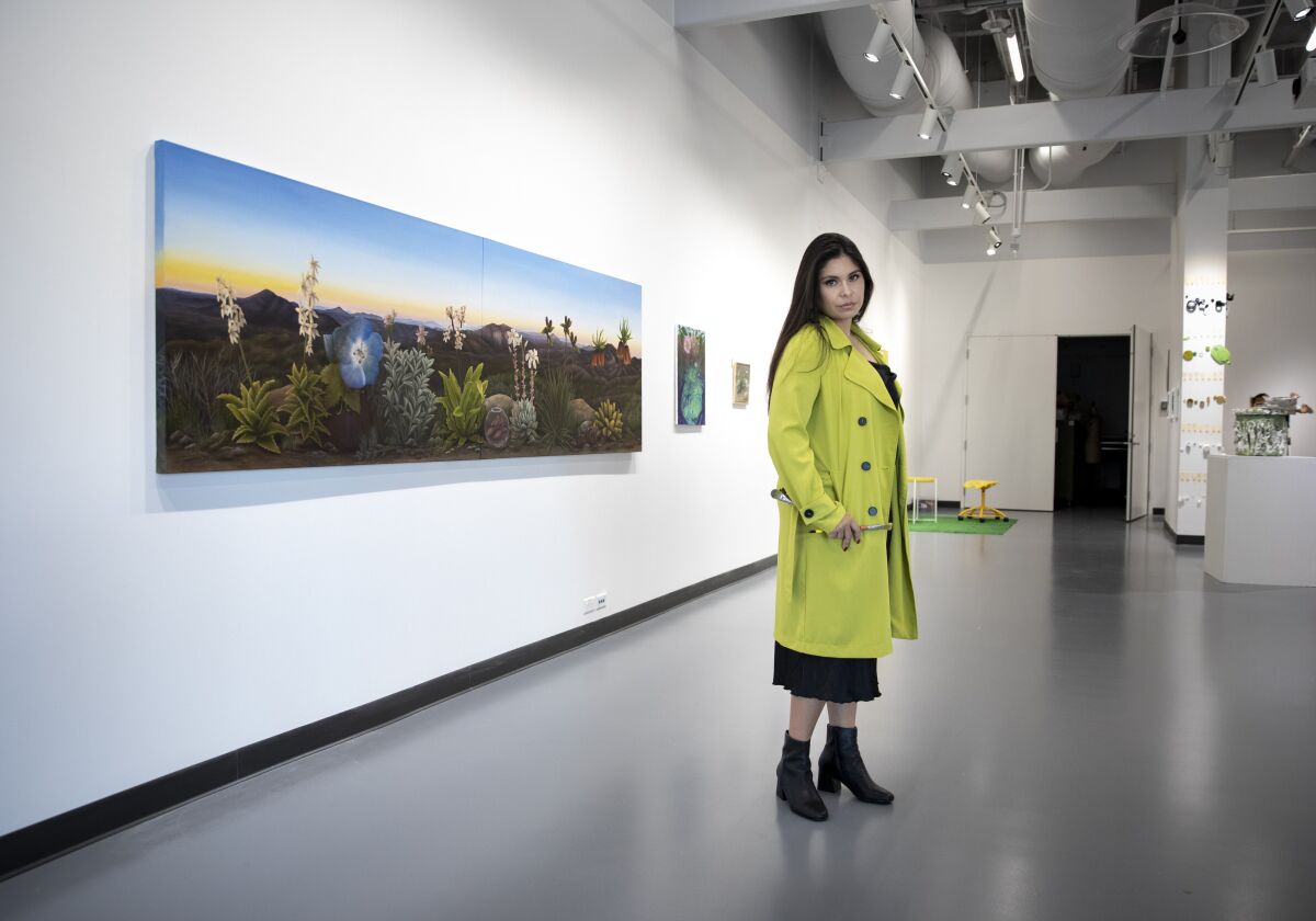 Amanda Kachadoorian stands in front of one of her large oil paintings, looking at the camera