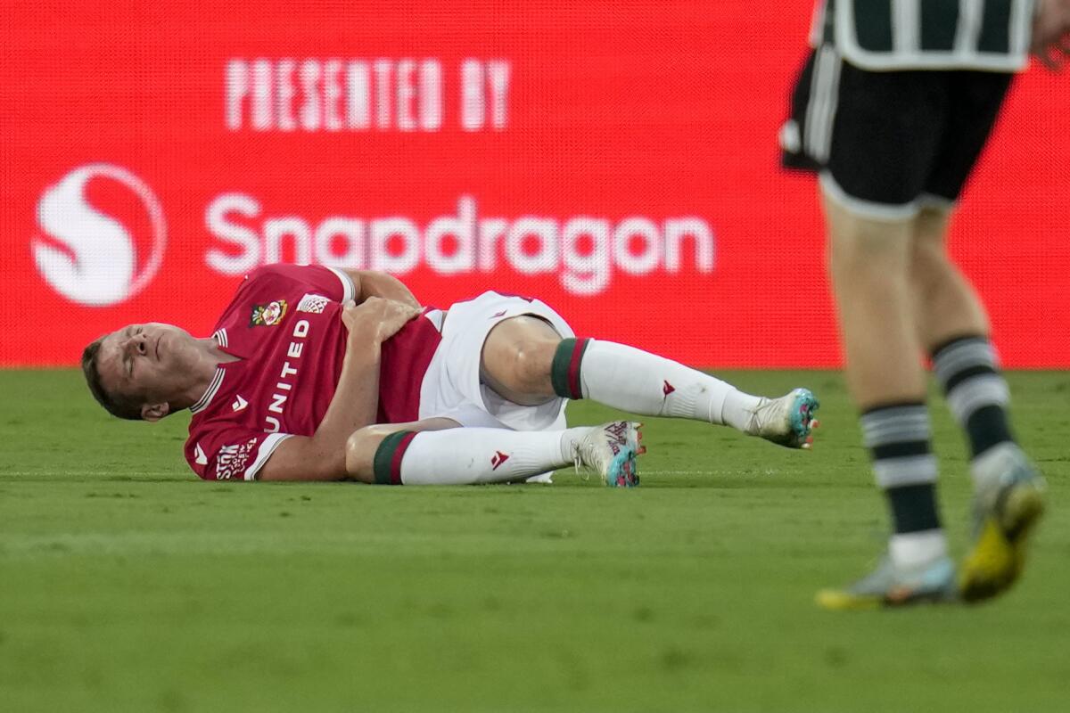 Wrexham forward Paul Mullin stays on the ground holding his side after an injury.