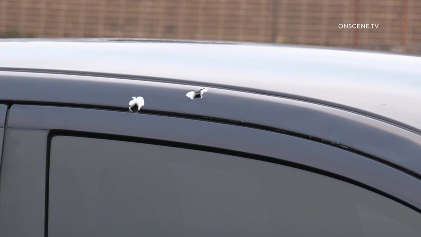 Two bullet holes above sedan door