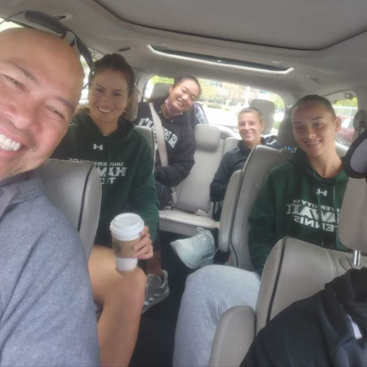 Hawaii women's tennis coach Jun Hernandez sits in a car with players during a road trip last year.