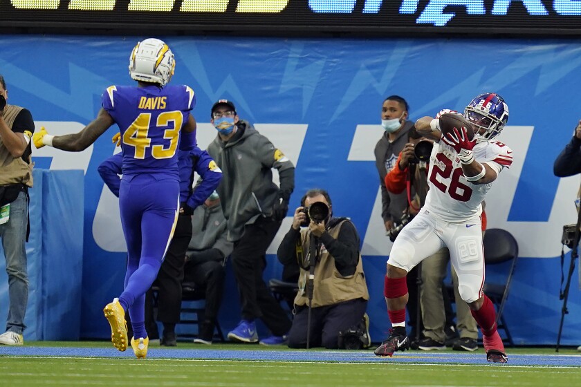 New York Giants running back Saquon Barkley (26) catches a touchdown in front of Los Angeles Chargers cornerback Michael Davis (43) during the second half of an NFL football game Sunday, Dec. 12, 2021, in Inglewood, Calif. (AP Photo/Gregory Bull)