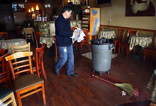 A person cleans up inside the Coffee House in San Gabriel, where a shooting late Thursday killed one person and wounded several others.