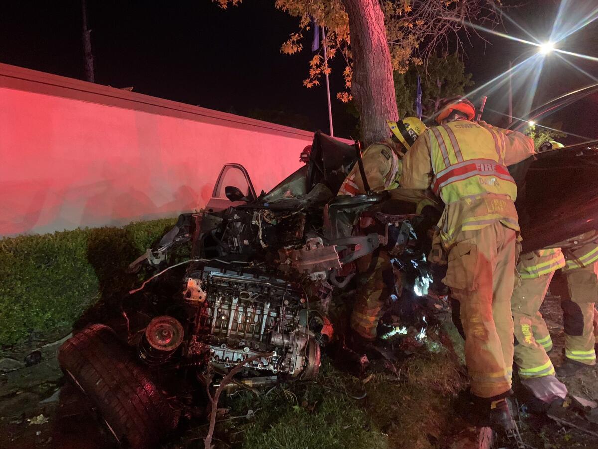 Costa Mesa fire crews extricate two people from a vehicle that collided into a tree on Baker Street Wednesday at 12:30 a.m.