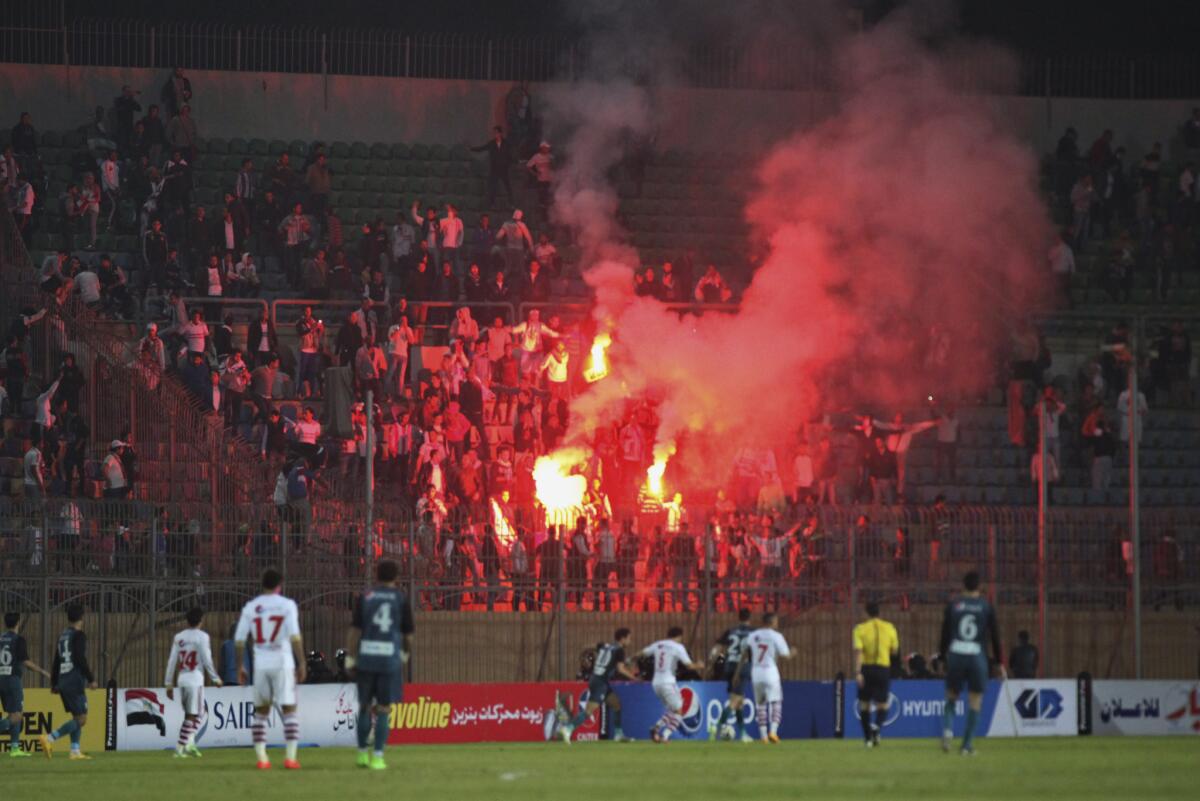 Soccer fans hold flares Feb. 8 as they watch a match at Air Defense Stadium in a Cairo suburb. A riot erupted outside the game, with a stampede and fighting between police and fans.