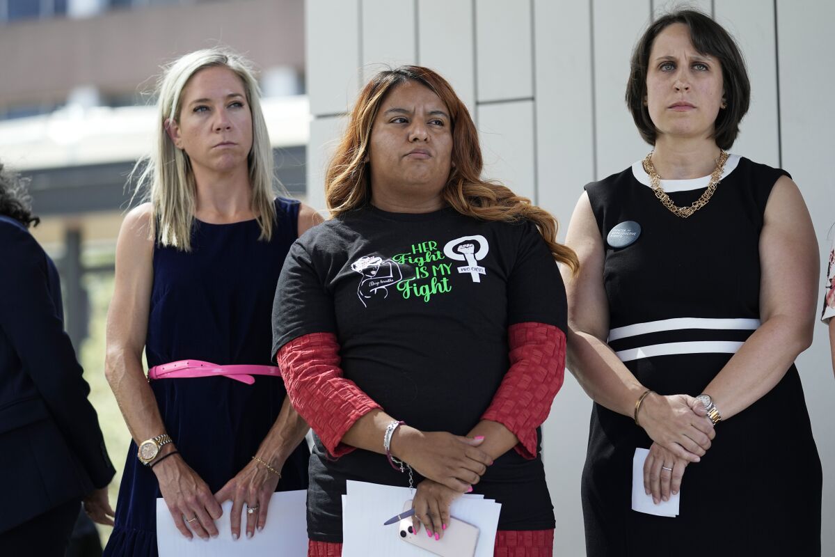 FILE - Amanda Zurawski, who developed sepsis and nearly died after being refused an abortion when her water broke at 18 weeks, left, and Samantha Casiano, who was forced to carry a nonviable pregnancy to term and give birth to a baby who died four hours after birth, center, stand with their attorney Molly Duane outside the Travis County Courthouse, Wednesday, July 19, 2023, in Austin, Texas. A Texas judge ruled Friday, Aug. 4, 2023, the states abortion ban has proven too restrictive for women with serious pregnancy complications and must allow exceptions without doctors fearing the threat of criminal charges. The challenge is believed to be the first in the U.S. brought by women who have been denied abortions since the Supreme Court last year overturned Roe v. Wade, which for nearly 50 years had affirmed the constitutional right to an abortion. (AP Photo/Eric Gay, File)