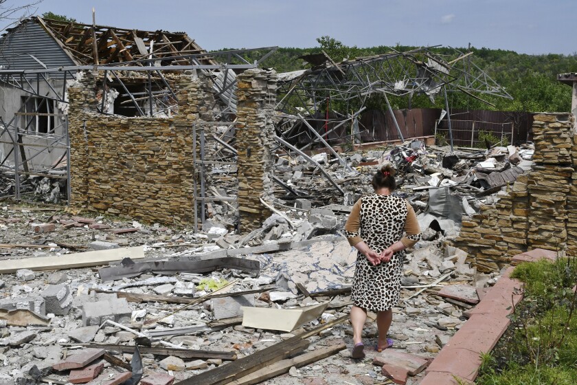 Woman walking past the rubble of a badly damaged building