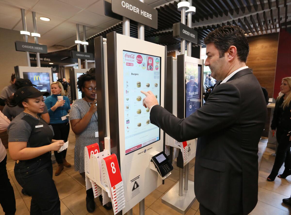 McDonald's Corp. Chief Executive Steve Easterbrook demonstrates a self-service kiosk at a McDonald's restaurant in New York.