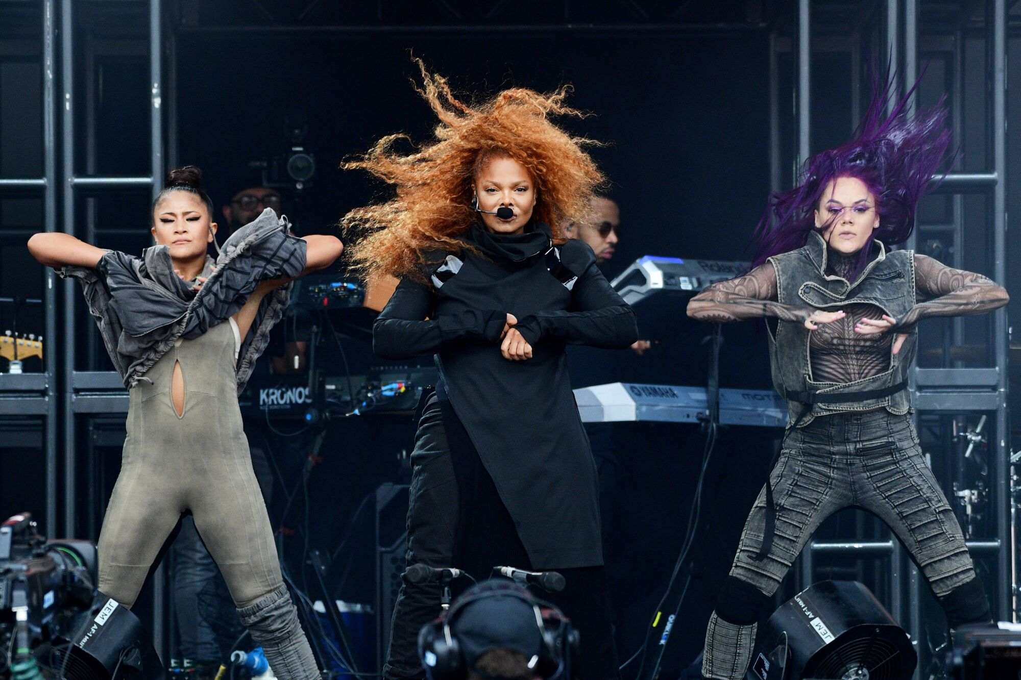 A woman with red hair dances onstage with two female backup dancers 