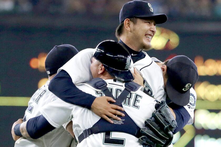 Mariners starter Hisashi Iwakuma, center, is mobbed by teammates, including catcher Jesus Sucre (2), after pitching a no-hitter against the Baltimore Orioles on Wednesday afternoon in Seattle.