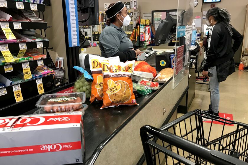 LONG BEACH, CALIF. - DEC. 16, 2020. A cashier helps a customer at the checkout stand in the Von's grocery store iin Long Beach on Wednesday, Dec. 16, 2020. (Luis Sinco/Los Angeles Times)